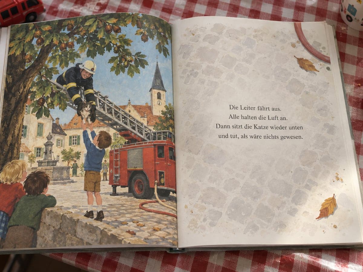 Aufgeschlagenes personalisiertes Kinderbuch zum Motiv Feuerwehr: links die Illustration, rechts der Text